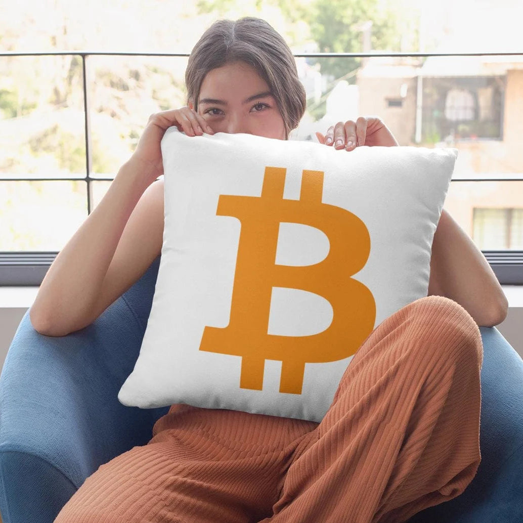 Person sitting on a blue chair holding a pillow with a Bitcoin symbol